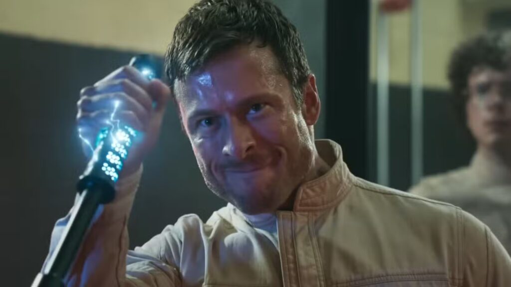 richards-grimacing-as-he-grabs-a-policemans-taser-wand-in-the-running-man-1024x576 Crítica de The Running Man: la sátira de un mundo que ya no distingue entre espectáculo y realidad