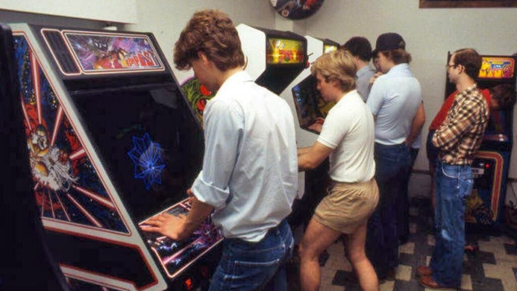 varios-jovenes-jugando-maquinas-recreativas-1024x576 Los templos de neón: las salas recreativas como catedrales de los 80